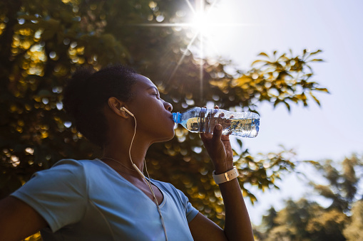 African American woman jogger drinking water hydrating