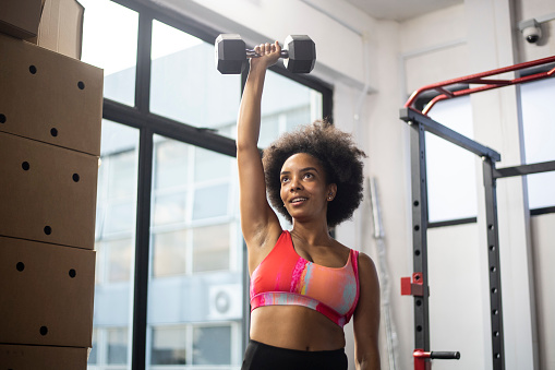 African American woman lifting weights in gym
