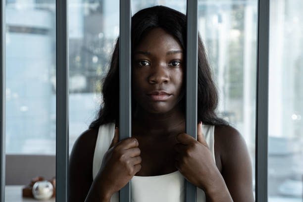 African American woman with a sad look behind iron bars stock photo