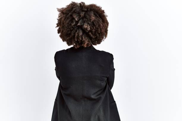 African american woman with afro hair wearing business jacket and glasses standing backwards looking away with crossed arms stock photo