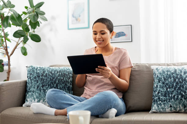 african american woman with tablet pc at home stock photo