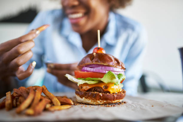 femme afro-américaine avec repas sans viande burger végétalien - eating burger photos et images de collection