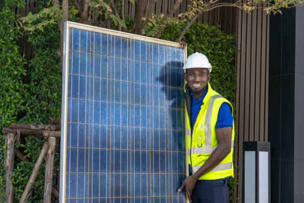 African American worker working on installing solar panel on the rooftop of the house for renewable energy and environmental friendly outcome stock photo
