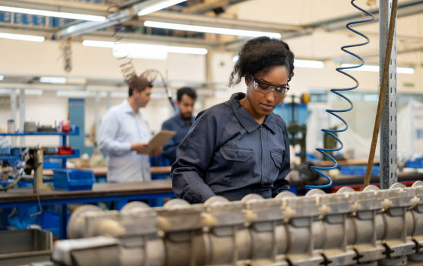 afroamerikanische junge frau arbeitet in einer montage produktion von wasserpumpen in einer fabrik - maschinenteil ausrüstung und geräte fotos stock-fotos und bilder