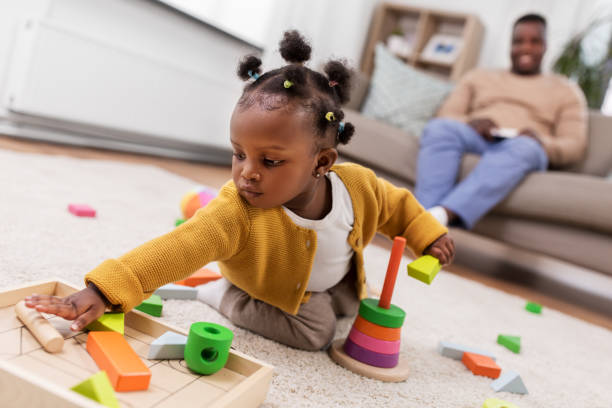 african baby girl playing with toy blocks at home stock photo