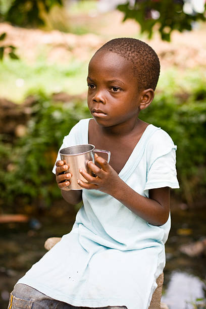 african boy holding a cup of water - africa cup stockfoto's en -beelden