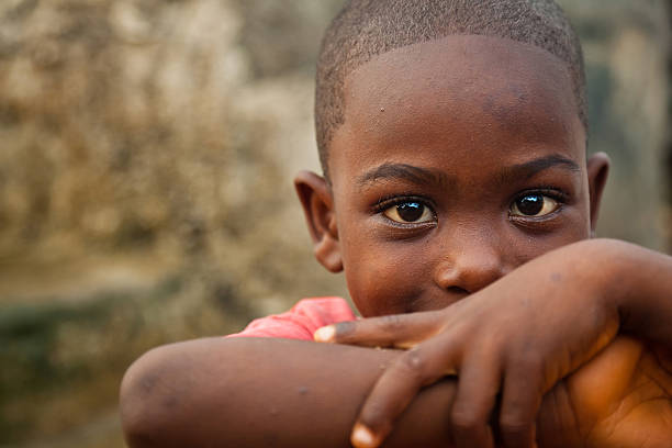African Boy A cute African boy leaning on his elbows and smiling at the camera. poverty stock pictures, royalty-free photos & images