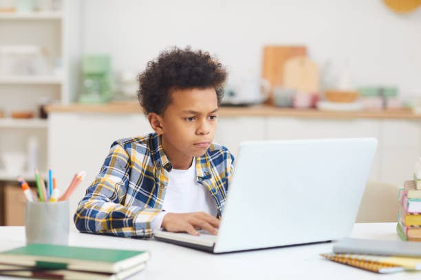 african boy using laptop for online class - jovem a escrever imagens e fotografias de stock