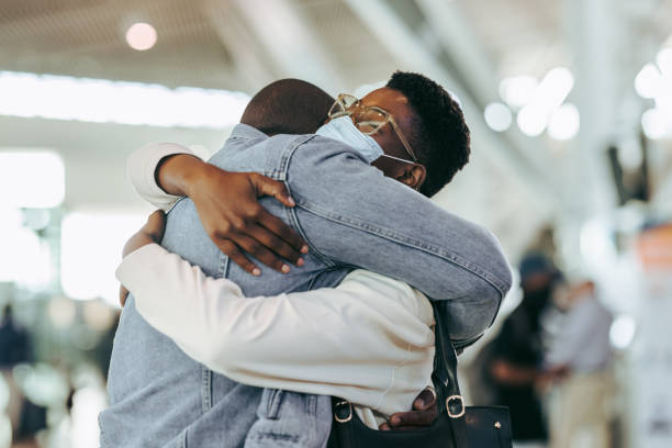 African couple reuniting at airport arrivals stock photo