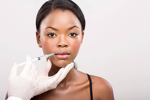 african girl receiving cosmetic injection on her lips stock photo