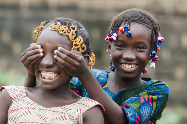 African Girls Playing Peekaboo Outdoors Laughing and Smiling Together (Happiness Symbol) stock photo