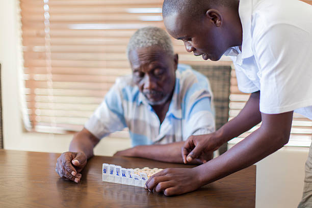 African grandson giving his grandfather medication. stock photo