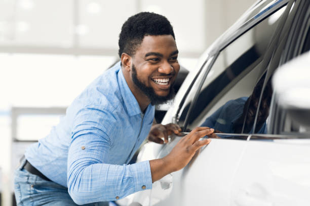 afrikaanse kerel die zijn nieuw voertuig in dealertoonzaal raakt - man with car stockfoto's en -beelden