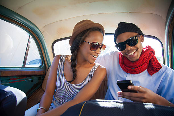 African hipster couple surfing the web on a phone stock photo