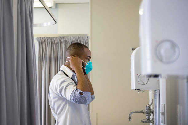 африканский врач-мужчина надевает медицинскую защитную маску - south africa covid стоковые фото и изображения