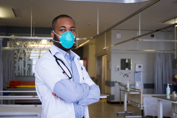African male doctor wears a protective mask Portrait of a young male healthcare worker wearing a protective mask. The corona virus outbreak around the world is a serious pandemic. Confident male doctor with face mask south africa covid stock pictures, royalty-free photos & images