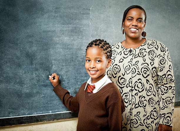 African Schoolgirl and Teacher at the Chalkboard stock photo