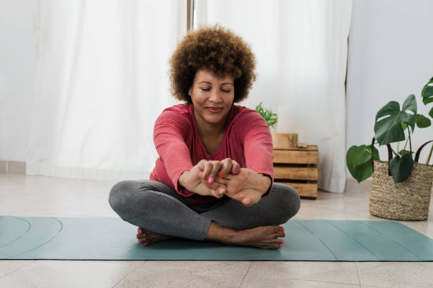 African senior woman doing yoga at home - Healthy lifestyle and mindfulness elderly concept - Focus on face stock photo