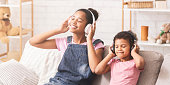 African sisters enjoying favorite music in headphones, panorama