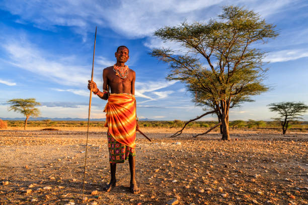 African warrior from Samburu tribe, central Kenya, East Africa African warrior from Samburu tribe standing on savanna and holding a spear, central Kenya. Samburu tribe is one of the biggest tribes of north-central Kenya, and they are related to the Maasai. maasai warrior stock pictures, royalty-free photos & images