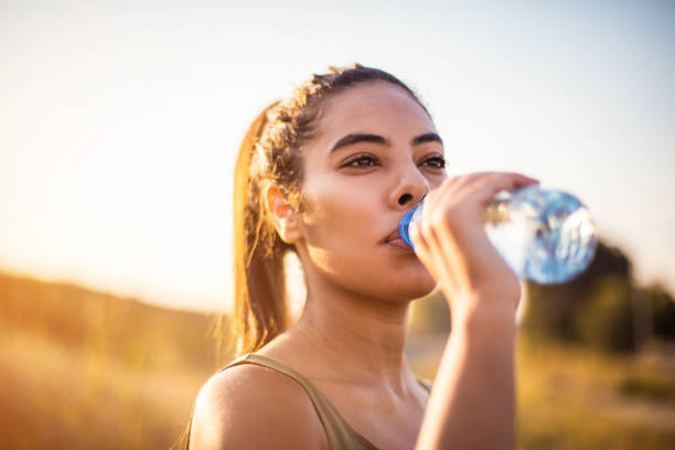 African woman drinking clean water after doing sport. stock photo