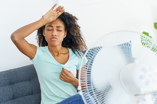 Black young woman suffering a heat wave at home