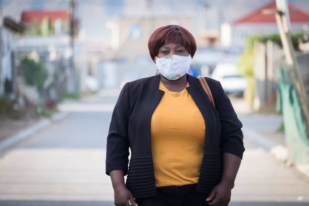 African woman with homemade facemask An African woman stands in the street in the township with her homemade facemask. African woman protecting herself against the virus. south africa covid stock pictures, royalty-free photos & images