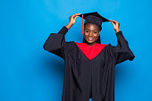 istock African-American beautiful woman in a black robe and hat, on a blue isolated background 1336055712