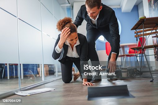 istock African-American Businesswoman Falling and Dropping Papers in an Office 1287054129