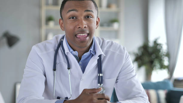 médico afroamericano hablando con el paciente, video chat - nurse talking to camera fotografías e imágenes de stock