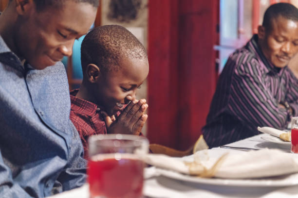 African-american doing prayer during thanksgiving dinner stock photo