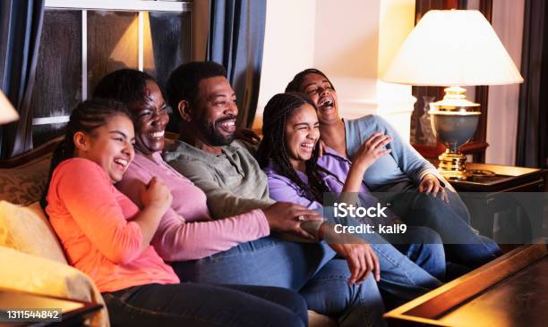 African-American family with three daughters watching TV