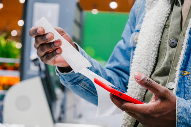 African-American man checks receipt total with smartphone stock photo