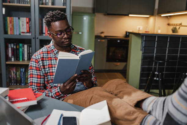 African-American man reading a book at home stock photo