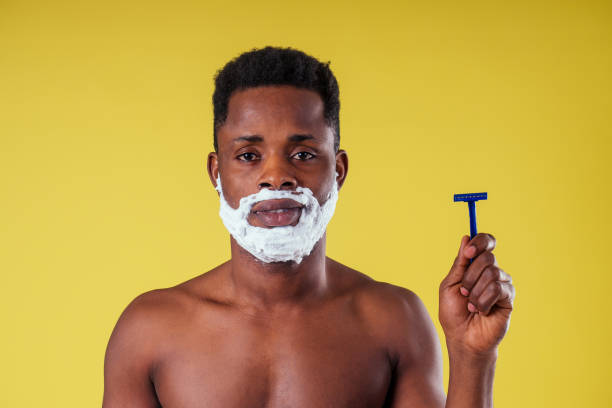 African-american man with razor and shaving foam on his face stock photo