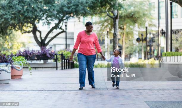 African-American mother and daughter walk in city park