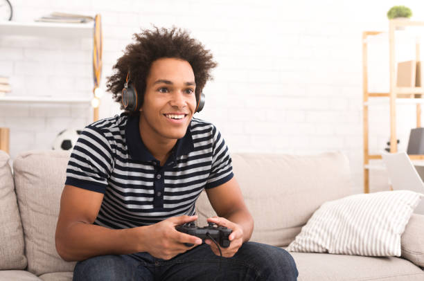 African-american teenager playing video games at home African-american teenager playing video games on console at home, copy space gamer playig against fans stock pictures, royalty-free photos & images