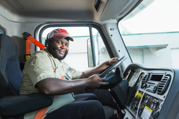 African-American truck driver in driver's seat A truck driver looking at the camera as he sits in the driver's seat. He is an African-American man in his 30s with a large build. He is wearing his seat belt. truck driver stock pictures, royalty-free photos & images