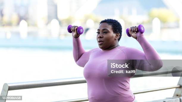 African-American woman lifting hand weights outdoors