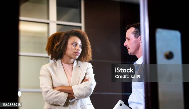 African-American woman talks with man in office lobby