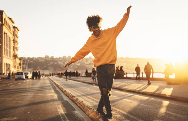 afro-amerikanische mann spaßig zu fuß in der innenstadt - glücklich junge kerl genießen zeit einen sonnenuntergang im freien - millennial generation lebensstil und positive menschen haltung konzept - urban lifestyle stock-fotos und bilder
