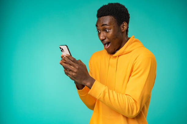 Afro american man using smartphone over isolated mint background stock photo