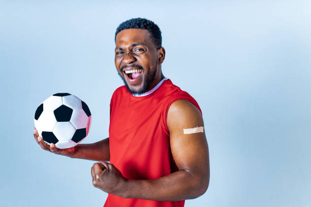 afro american sportsman showing his arm after receiving a vaccine in studio stock photo