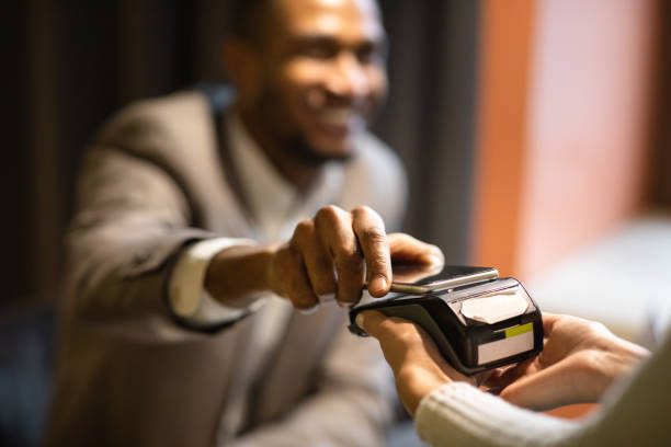 hombre de negocios afro pagando con su celular en el bar - estación edificio de transporte fotografías e imágenes de stock