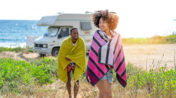 Afro couple in love enjoying their romantic summer vacation with camper . stock photo
