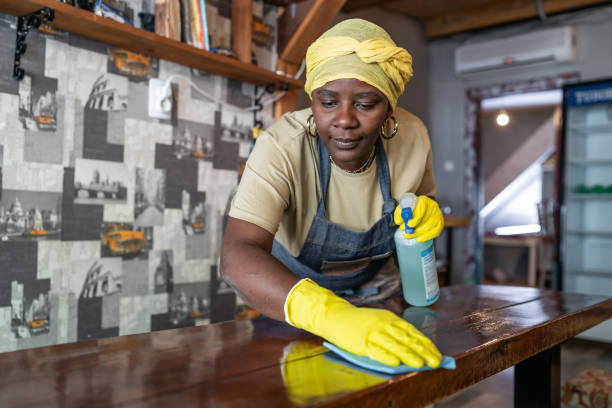 Afro female maid working at hostel disinfecting and preparing for the hostel guests after reopening stock photo