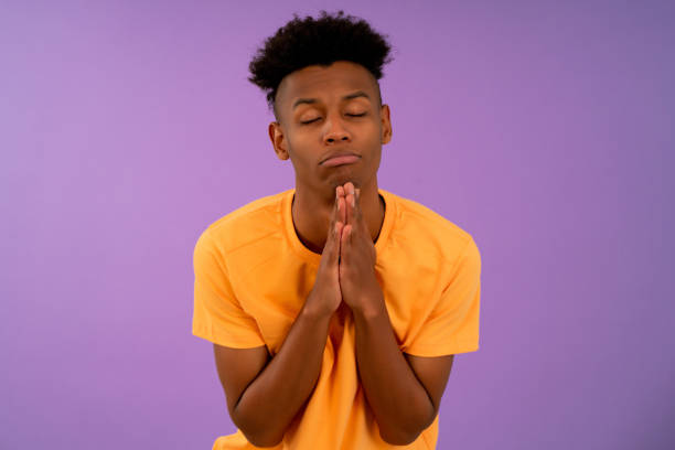 Afro man keeping hands together asking something. Portrait of a young afro man keeping hands together asking something while standing against an isolated background. prayer request stock pictures, royalty-free photos & images