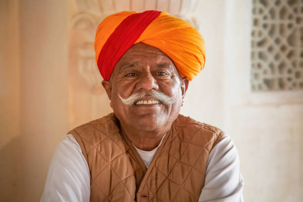 Aged man with facial hair and traditional saffron turban in close up portrait view at Rajasthan India stock photo