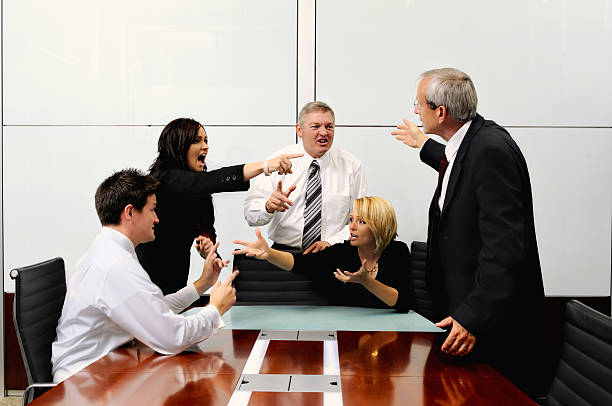 Agitated business people at a meeting pointing at each other stock photo