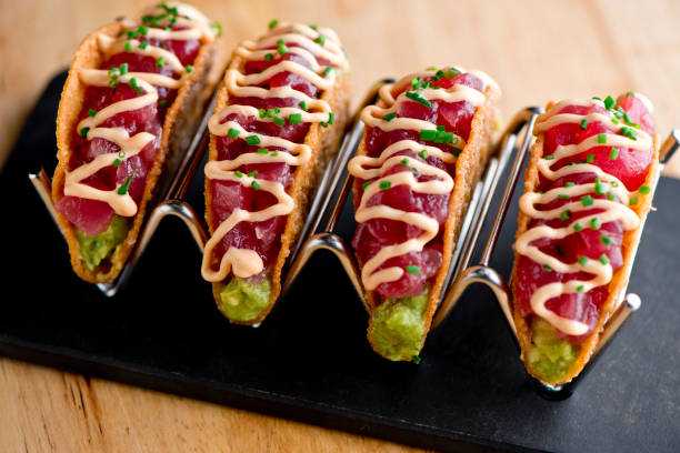 Ahi tuna tacos. Tuna tacos served in crispy shells with spicy wasabi sauce, avocado sliced and shisito leaves. Classic Japanese restaurant or American steakhouse appetizer favorite. stock photo